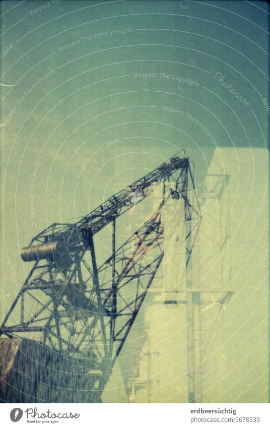 Harbor crane in double exposure in front of a yellowish sky Harbour container port Dockside crane lines Blue sky Yellowness Water Economy Trade Logistics