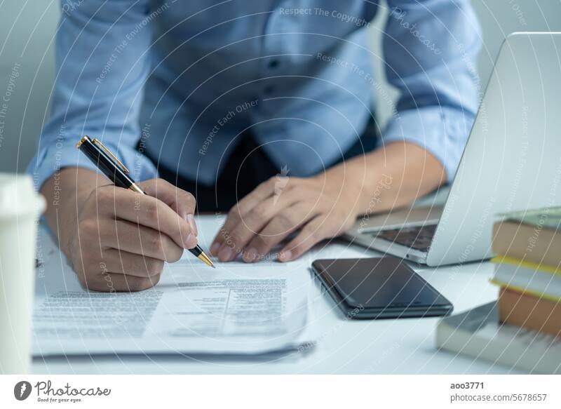Male hand holding a pen to write a document or sign a business or legal contract. Checklist of financial documents and market reports plan student success