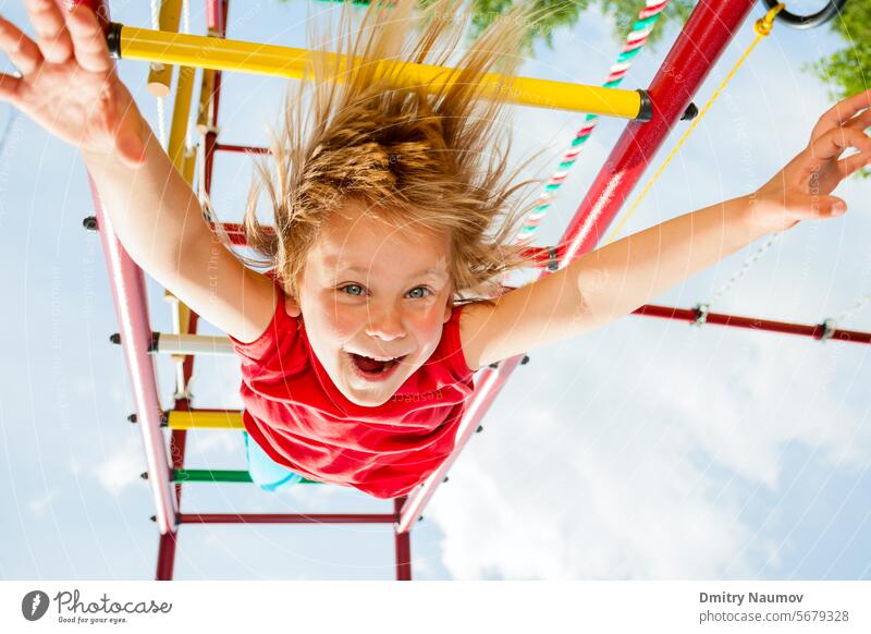 Little girl having fun playing on monkey bars activity caucasian cheerful child childhood climb climbing frame cute emotion enjoy exercise gripping hang