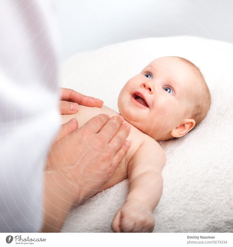 Three month baby girl is receiving chest massage from a female massage therapist 0-6 months abdomen abdominal alternative body care caucasian child doctor hand