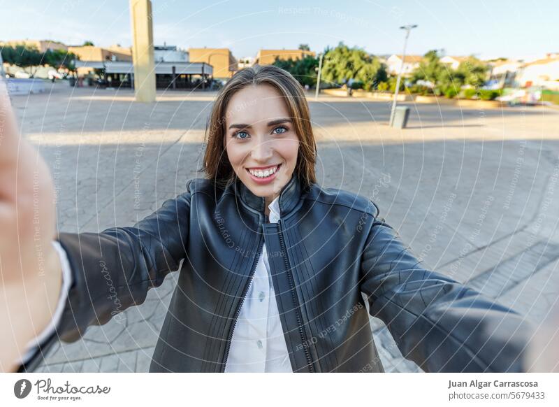 smiling young woman taking a selfie in the city happy female street lifestyle girl attractive outdoors portrait social media funny photo fashion people camera