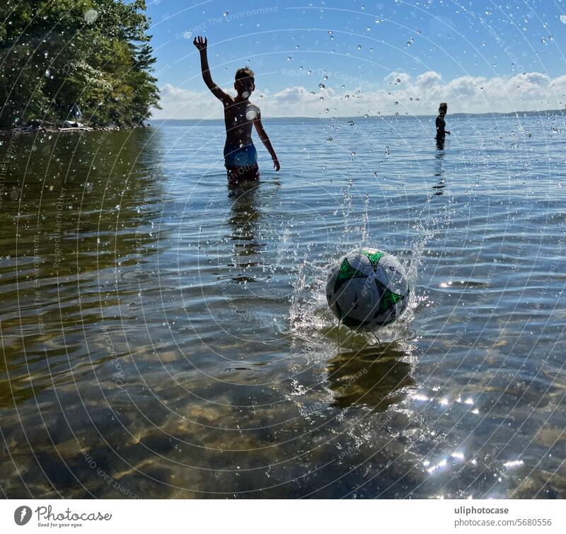 Backlit boy throwing a ball onto the water in the direction of the photographer Ball Backlight at the water Ball game Beach ball silouettes