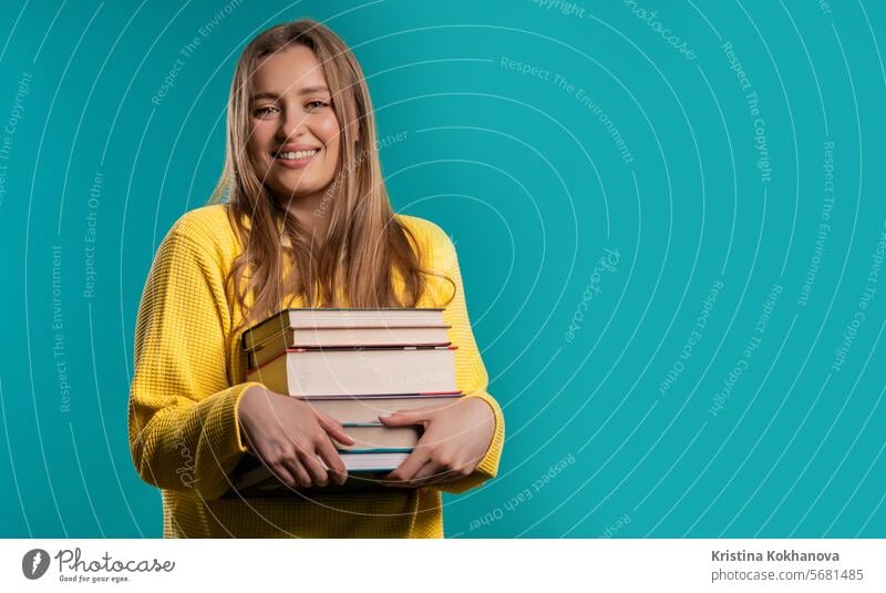 Happy student woman with stack books from library, blue background. Copy space american arms attractive beautiful casual clever college conception difficulty