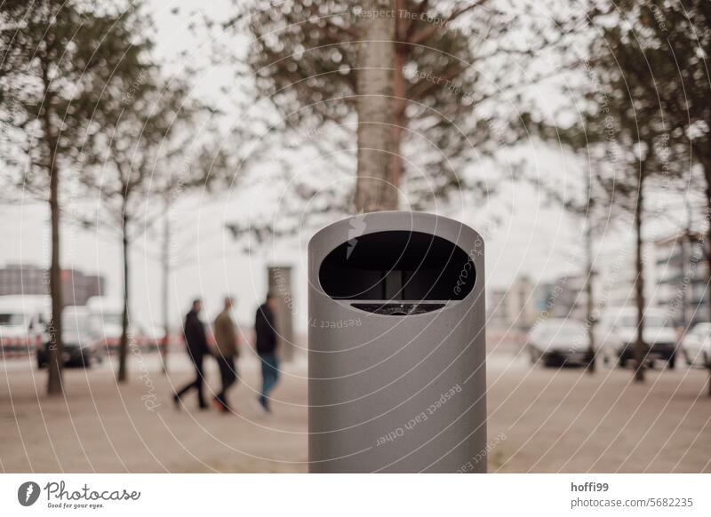 Trash can in blurred urban environment with passing group of people, cheetah cars and young trees rubbish bin Wastepaper basket litter bins Dispose of Recycling