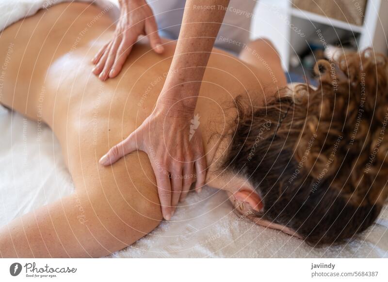 Crop masseuse kneading back of client in hospital room women osteopath patient appointment massage shoulder session manual therapy female adult medicine lying