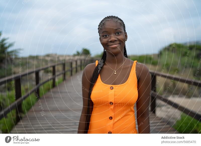 Smiling black woman standing on wooden footbridge lady style outfit plaited hair boardwalk smile cheerful positive happy mountain female nature glad walkway