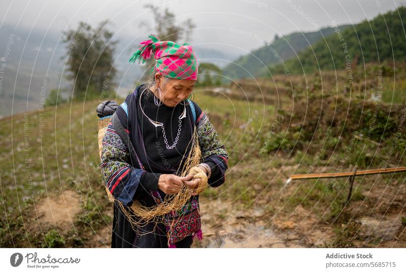Focused ethnic middle aged woman with fiber thread concentrate agriculture field tradition countryside water plant process female mature headscarf hobby rural