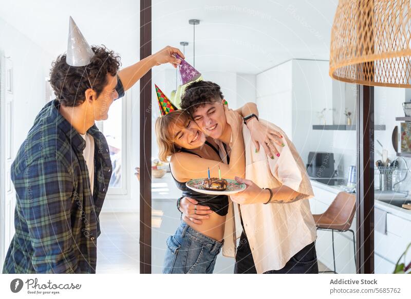 Happy friends having fun moment together in modern kitchen woman celebrate birthday delight hug cone hat cake smile party happy relationship love embrace young