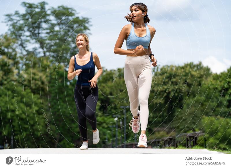 Cheerful sportswomen jogging on road - a Royalty Free Stock Photo from  Photocase