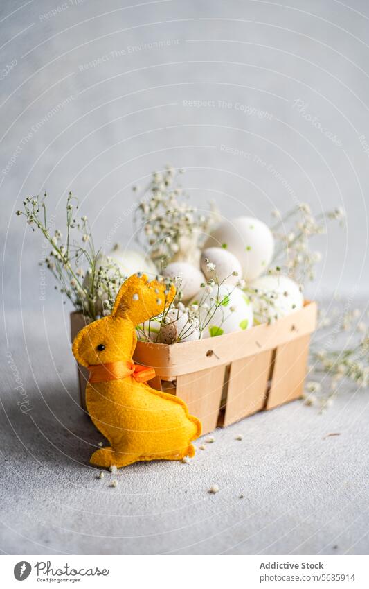 Plush Easter bunny with decorated eggs and baby's breath easter plush yellow basket grey background texture spring holiday celebration festive decoration