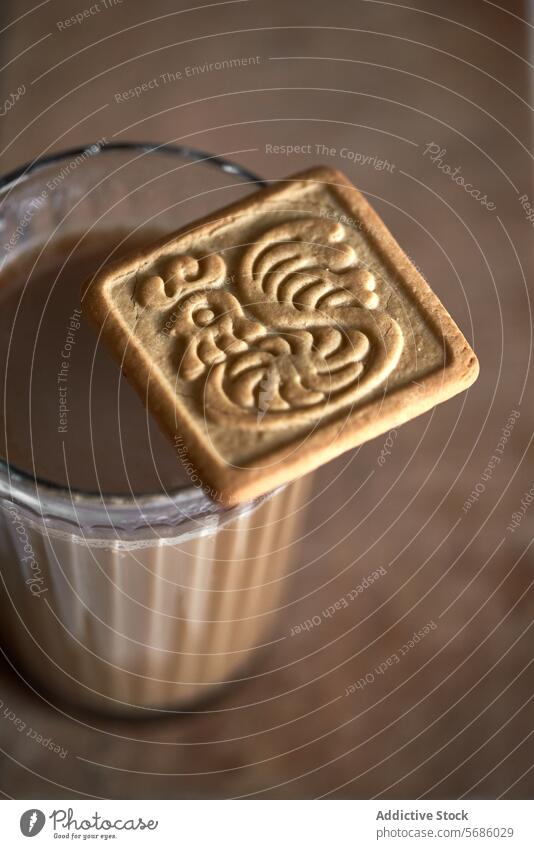 Embossed cookie on a glass of chocolate milk square embossed close-up detailed dessert snack beverage dairy sweet tasty treat drink brown texture pattern design