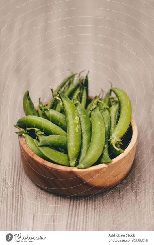 Fresh green peas in a wooden bowl on a wooden background ripe natural rustic textured fresh vegetable organic healthy legume raw close-up food pod ingredient