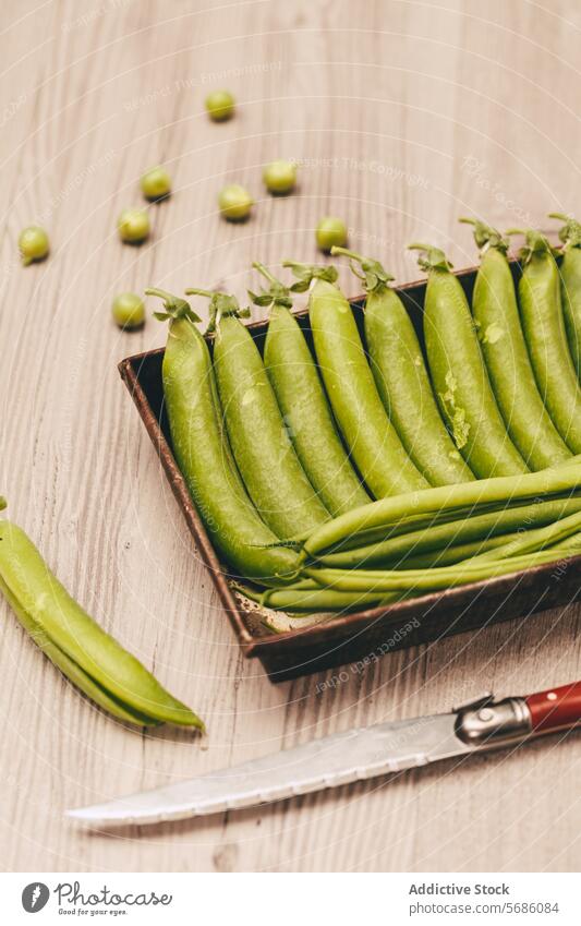 Fresh green peas in a rustic tray with knife on wooden surface tabletop ripe vegetable food raw healthy ingredient fresh organic nutrition dietary fiber legume
