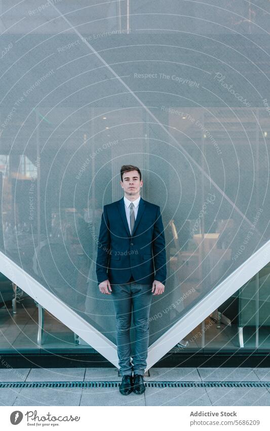Young businessman looking at camera standing in front of a modern building suit architecture geometric contemporary madrid spain stylish young confident