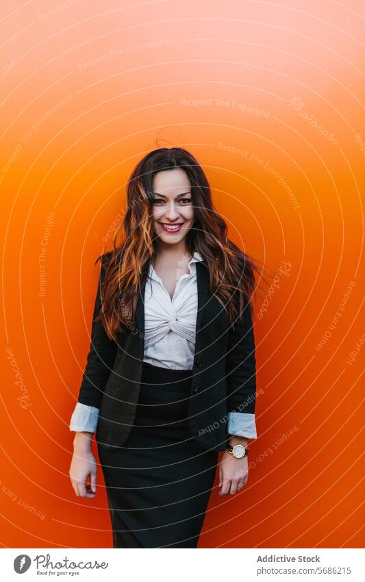 Confident businesswoman looking at camera against an orange background professional smile confident suit madrid spain wall young adult female fashion style