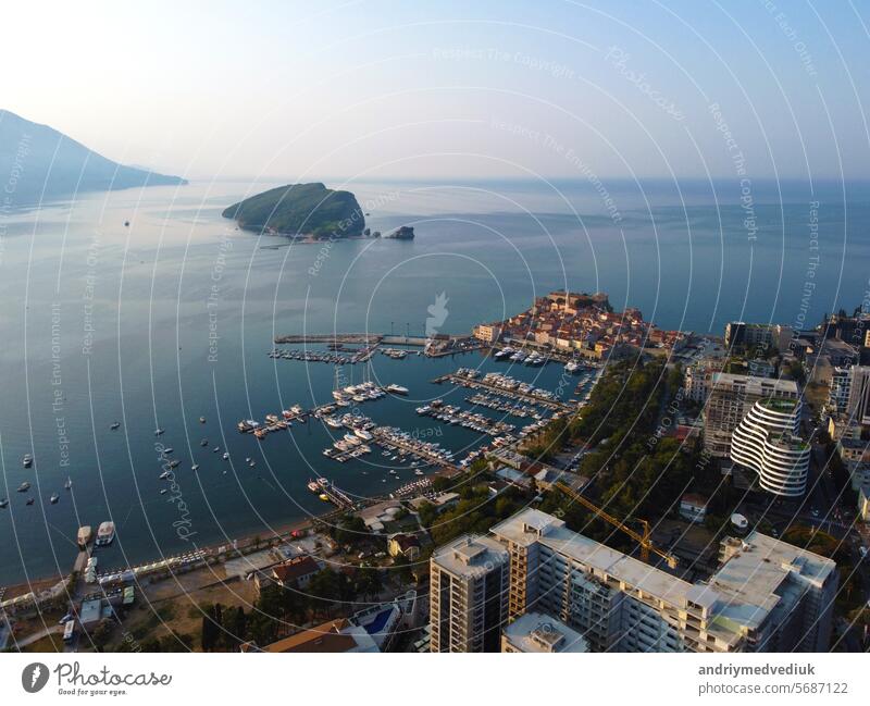 Aerial view of modern and old town cityscape of Budva, Mongenegro on Adriatic Sea coast and Saint Nikhola's island on background on summer sunny day. Center of tourism and popular sea resort.
