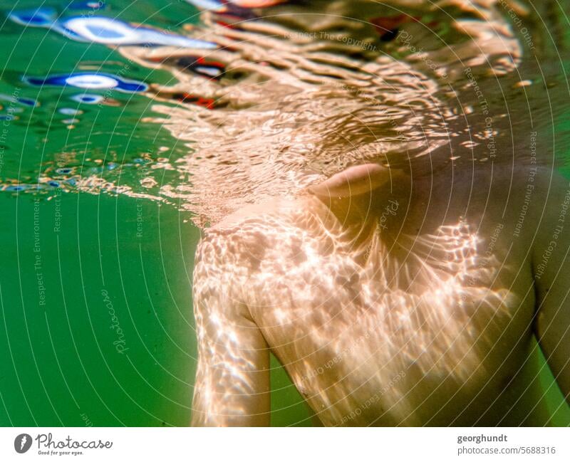 Boy underwater, head not recognizable. The upper body and arms are reflected in the lower side of the water surface. Water Lake vacation be afloat bathe