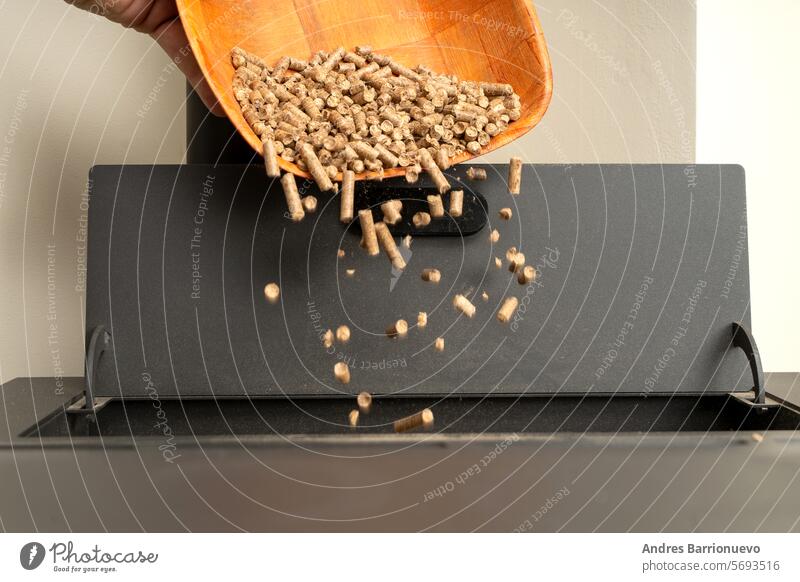 Closeup of a wooden basket filling a pellet stove. Sustainable and ecological heating pellets granules closeup alternative compressed environment energy hand