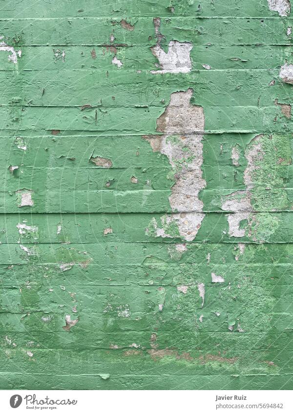 texture of a green painted concrete block wall with paint flaws and chipping, cement wall in bad condition damage broken background rough old grunge surface