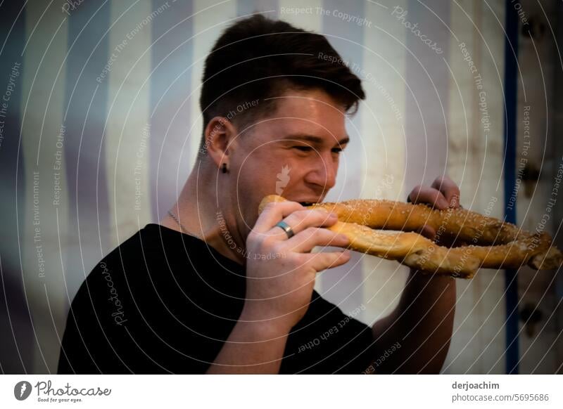Typical German / Young man bites into a large pretzel with relish.  Of course it's from Franconia. Pretzel Appetite Delicious Eating Meal Nutrition Food