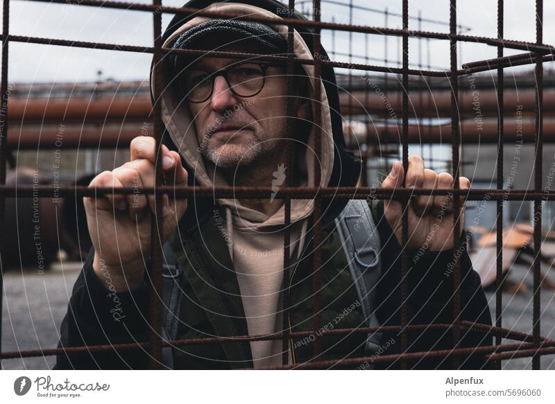 Warmly dressed man behind bars | Glückauf! Man penned Penal camp Captured jail Barrier Freedom Border captivity Protection Safety Fence Fear cordon Metal Threat
