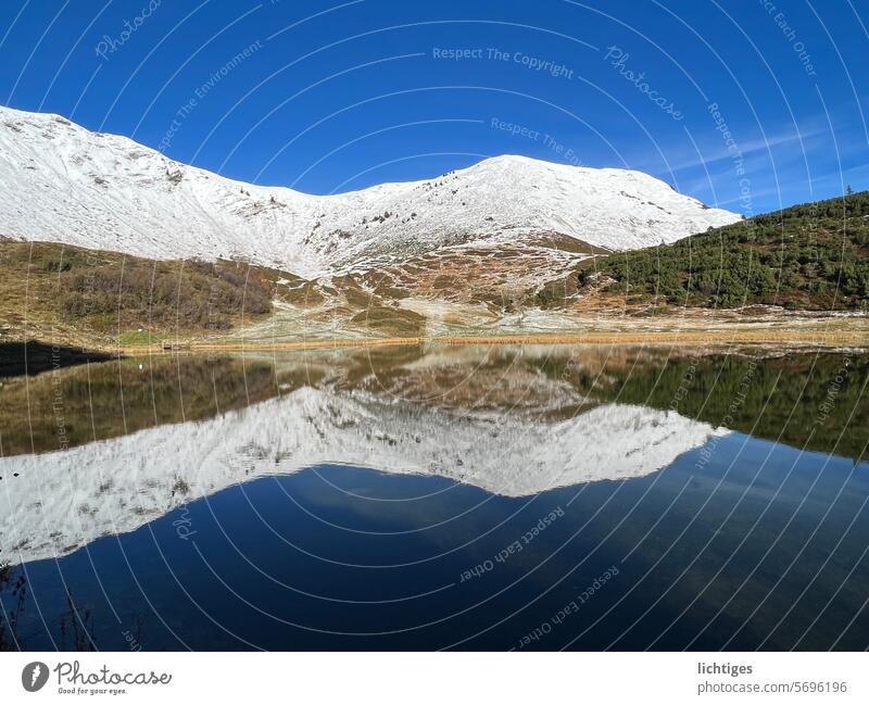 Snow mountain and grass green reflected in the mountain lake reflection Nature drama Clarity