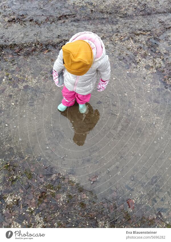 Child stands in a dirty puddle and is reflected slush Autumn Puddle Mud Reflection Wet Rain Dirty Bad weather Rubber boots Weather Winter