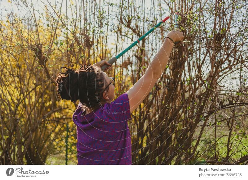 Woman pruning bushes on her allotment during springtime Gardening Equipment Leisure Activity Lifestyles back yard Day Outdoors nature garden community garden
