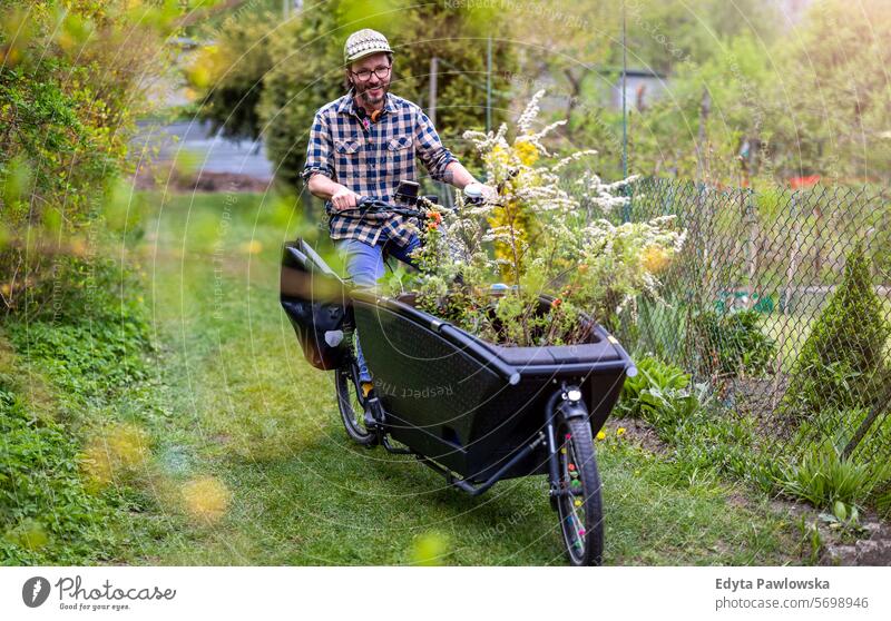 Man with a cargo bike working on his allotment bicycle Gardening Equipment Leisure Activity Lifestyles Day Outdoors nature garden community garden chores