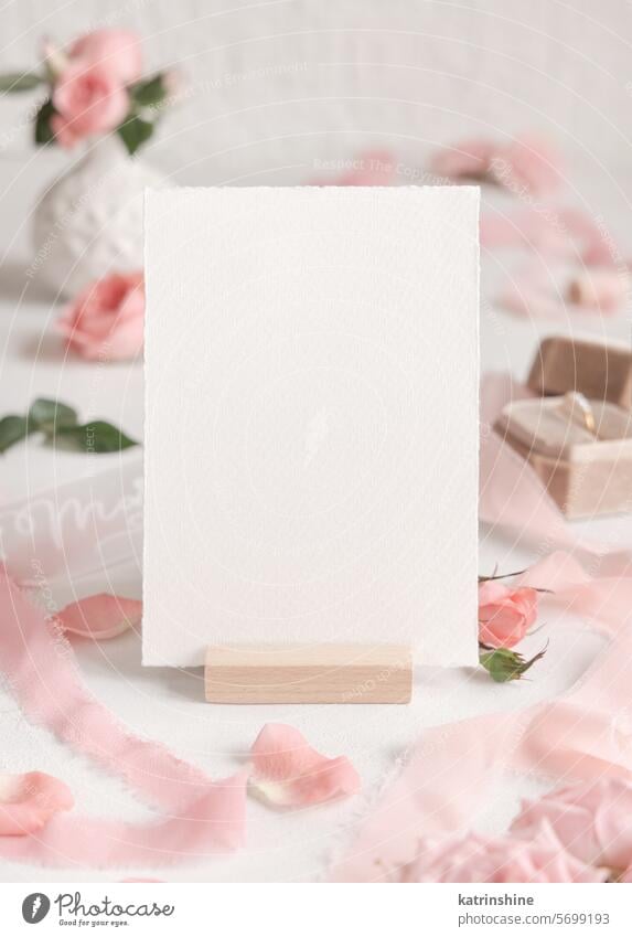 Blank card near light pink roses, petals and silk ribbons close up, wedding mockup WEDDING flowers romantic ring white engagement vertical paper valentine