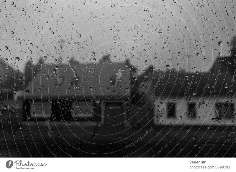Black and white photo, houses behind a window pane with many raindrops Black & white photo black-and-white Black and white photography Black and white image