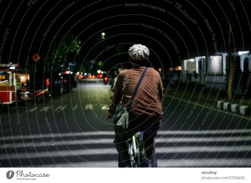 rear view of man riding bicycle in the middle of the road at night people adult one person cycling outdoors young adult illuminated transportation city life