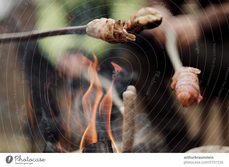 Grilling sausage and bread over a campfire in a stone circle in the countryside Camp fire atmosphere Stone stones Meadow Nature Experiencing nature