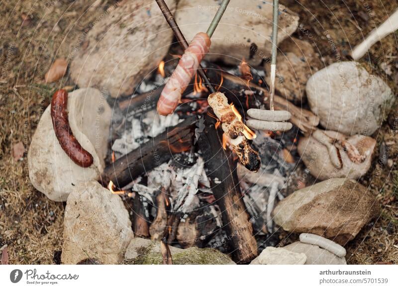 Grilling sausage and bread over a campfire in a stone circle in the countryside Camp fire atmosphere Stone stones Meadow Nature Experiencing nature