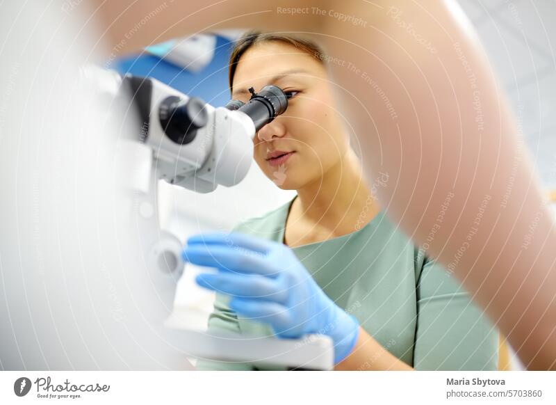 Gynecologist examines a patient using microscope in a gynecological chair. Doctor performs a colposcopy on a young girl in a modern medical office. Diagnosis of cervical cancer.