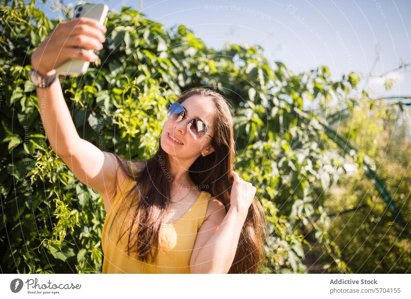 Young woman enjoying summer and taking selfie outdoors smartphone garden sunny capturing moment cheerful young female taking photo leisure casual happiness