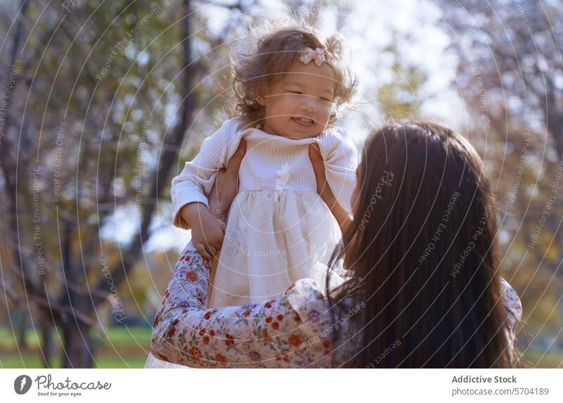 Anonymous mother and daughter bonding in a sunny park nature california usa ethnic enjoy outdoor trees happiness family love affection child parent woman