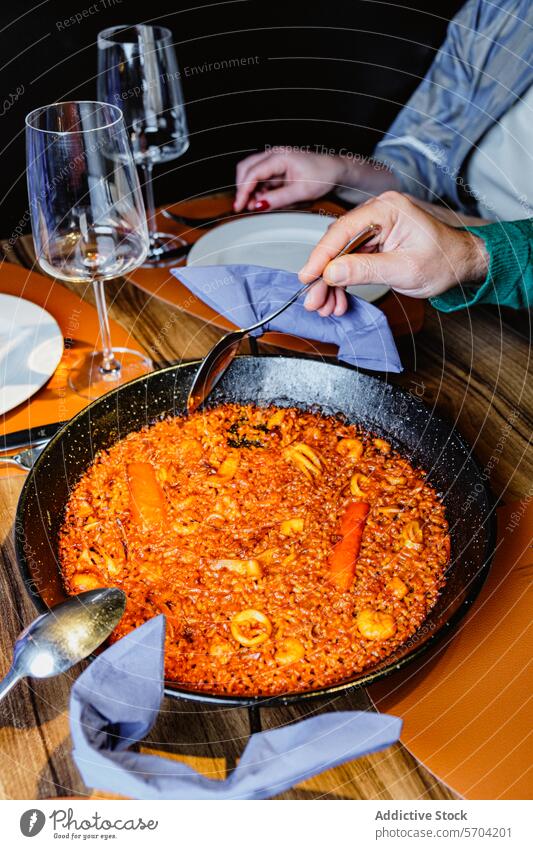 Enjoying a traditional Spanish seafood paella meal table dining wine glass person eat enjoy spanish cuisine restaurant rice shrimp mussel carrot squid spoon
