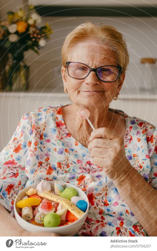 Senior woman enjoying sweets with a heartwarming smile elderly senior lollipop candy colorful glasses cheerful happiness dessert snack treat aged mature bowl