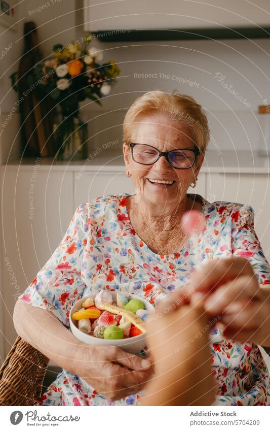 Elderly woman smiling while receiving a fruit bowl elderly glasses fresh salad kitchen cozy joyful happiness senior health nutrition lifestyle care giving