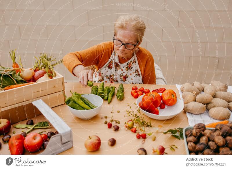 Elderly woman preparing fresh vegetables in kitchen senior glasses chopping healthy produce cooking food preparation elderly nutrition lifestyle apron carrots