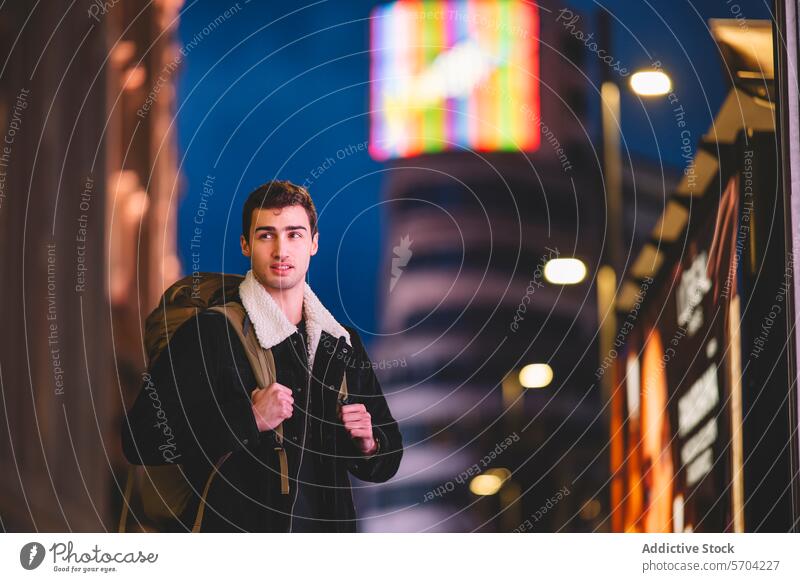 Young man exploring Madrid at night with vibrant neon signs illuminating the background young illumination backpack urban adventure city male adult travel