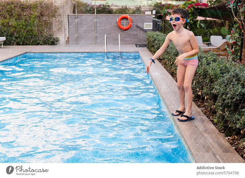 Young boy ready to jump into the outdoor pool swim dive goggles swimwear summer water fun leisure happy childhood activity swimming position edge poolside