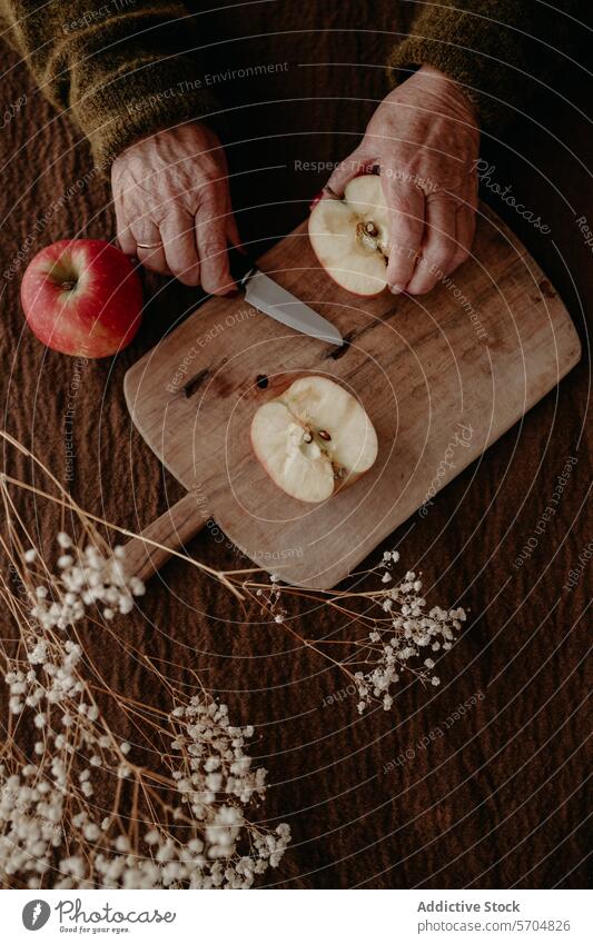 Elderly hands slicing an apple on a wooden board elderly cutting rustic homely aged close-up fresh serene cutting board slice fruit knife preparation food table
