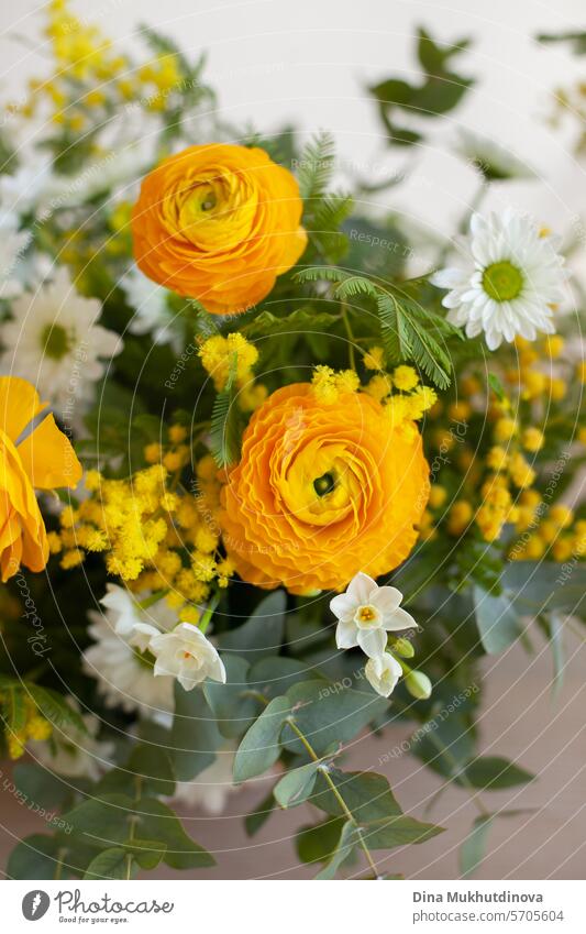 easter home decor. beautiful flower bouquet with yellow ranunculus and white spring flowers on white beige neutral background copy space top and bottom. Floral arrangement vertical backdrop.