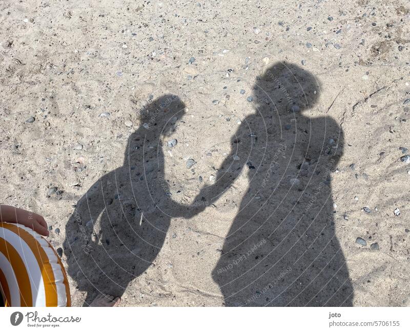 Mother and child as shadows on the sand at the beach while bathing Silhouette Shadow maternity mother and child two people hold hands Child Together Happy