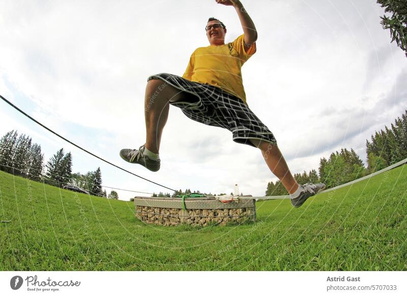 Ein junger Mann hat Spaß auf einer Slackline mann slackline slacken seil balancieren balance sport freizeit freizeitsport aktiv aktivität bewegung bewegen spaß