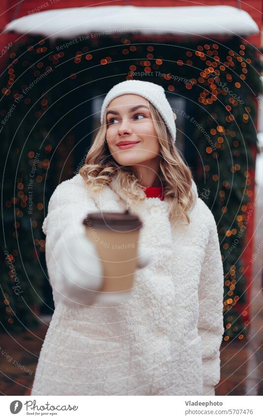 Woman in white wool mittens and fur coat holding take away coffee cup outdoors woman winter hand close-up fashion hat blonde holiday pine fir branch paper tea