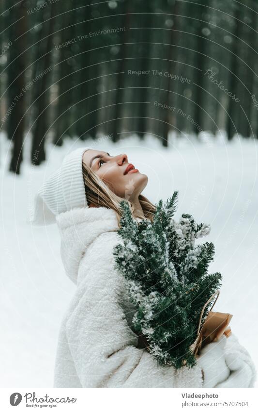 Happy young woman catching snowflakes with mouth in winter forest careless tongue happy person fun fur coat moment emotional outdoors walking cold season fir