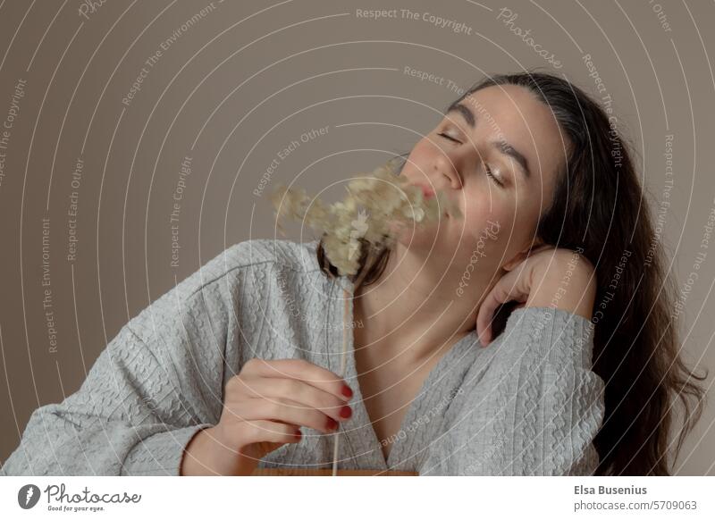 Woman relaxes, enjoys Human being Flower Dried flower Plant Beige To enjoy eyes closed middle age at home comfort Positive dark hair indoors Cozy